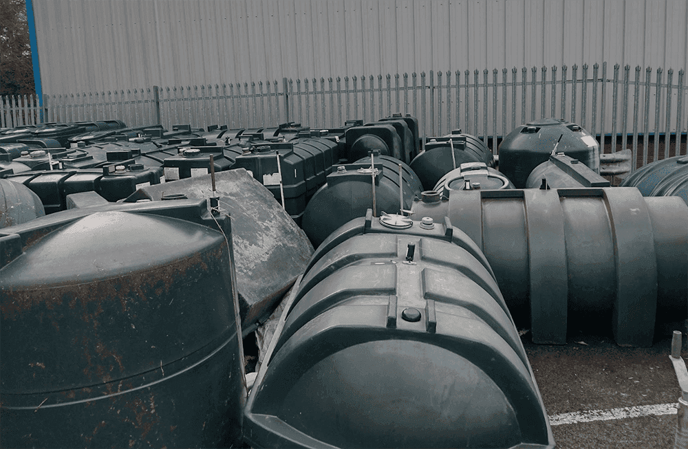 Collected plastic and steel heating oil tanks awaiting recycling at a MacWaste facility