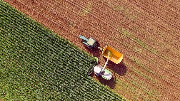Aerial view of a tractor harvesting a crop field