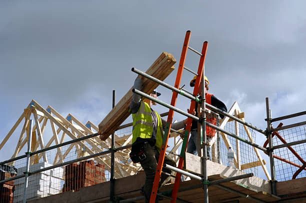 Construction workers on scaffolding at a house build