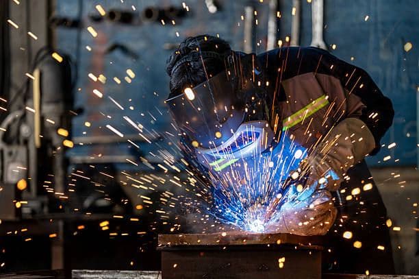 Factory worker welding in an industrial workshop
