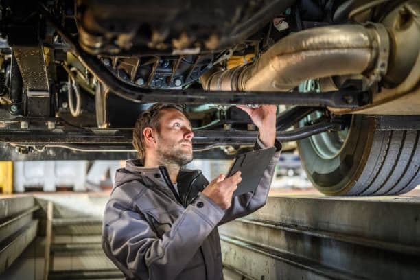 Mechanic inspecting the underside of a vehicle on a ramp