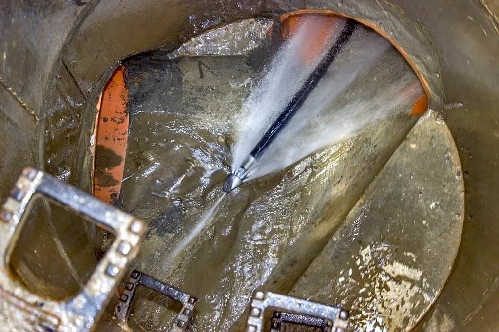 High-pressure water jetting nozzle clearing a blocked pipe