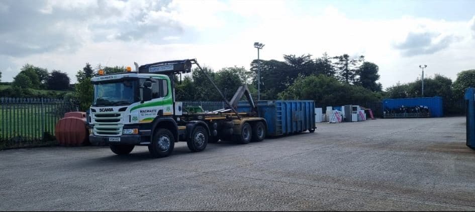 MacWaste hookloader vehicle lifting a roll-on/roll-off container